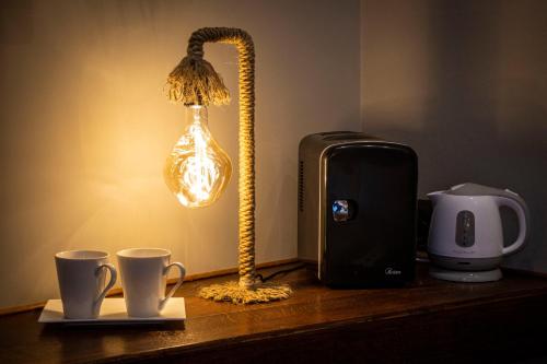 a table with a lamp and two cups on it at Splendid Room Suites in Turin