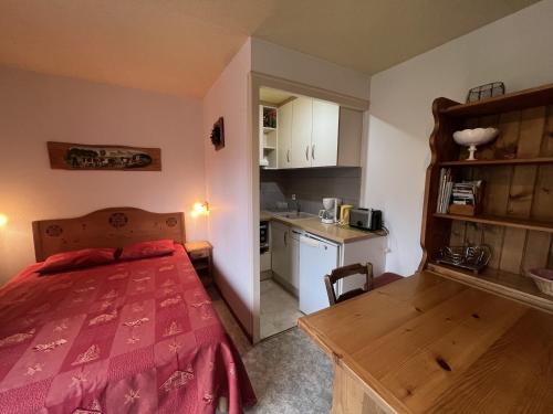 Il comprend une petite chambre avec un lit rouge et une cuisine. dans l'établissement Gemeaux S, studio proche pistes de ski et village, à La Clusaz