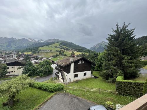 une maison dans un village avec des montagnes en arrière-plan dans l'établissement Gemeaux S, studio proche pistes de ski et village, à La Clusaz