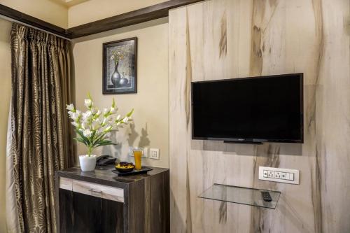 a living room with a flat screen tv on a wooden wall at Super Townhouse OAK Regal Inn Near Sant Tukaram Nagar Metro Station in Chinchiwad