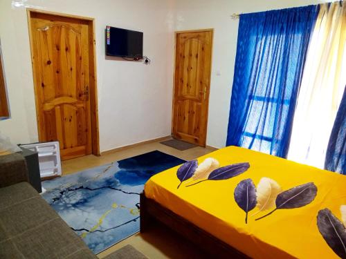 een slaapkamer met een geel bed met bladeren erop bij RÉSIDENCENGUARY in Dakar