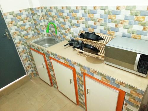 a kitchen with a sink and a microwave at RÉSIDENCENGUARY in Dakar