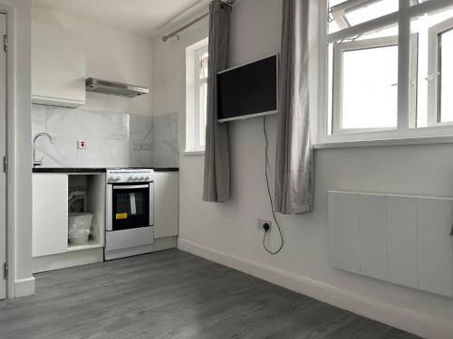 a kitchen with white appliances and a window at Remarkable 1-Bed Studio Apartment in Redbridge in Ilford