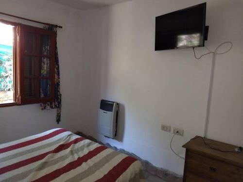 1 dormitorio con 1 cama y TV en la pared en Unser traum en Villa General Belgrano