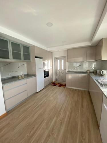a large kitchen with white appliances and wooden floors at Vivenda Caixilão casa com 3 quartos in Viana do Castelo