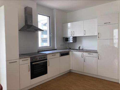 uma cozinha branca com armários brancos e uma janela em Moderne Alpenblick Apartment em Friedrichshafen