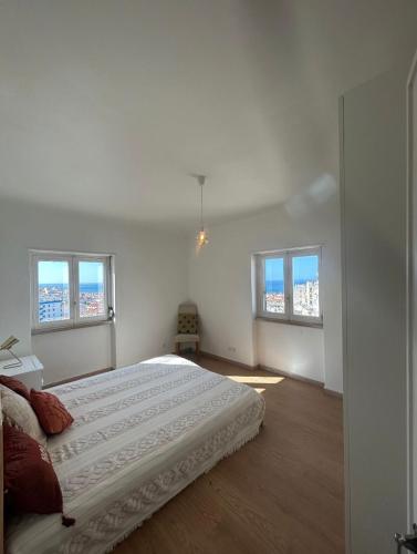 una camera bianca con un letto e due finestre di Portas da Vila a Sesimbra