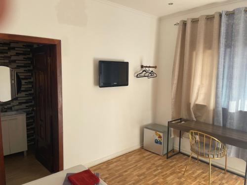 a living room with a tv on the wall at Hotel Kenito in São Tomé