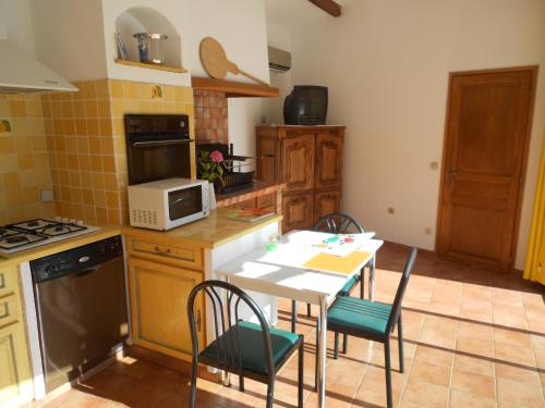 une cuisine avec une table et des chaises et un micro-ondes dans l'établissement VILLA AVEC PISCINE PRIVATIVE et EXCLUSIVE avec PARKING, à Roquefort-les-Pins