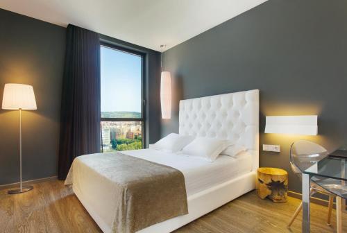 a bedroom with a white bed and a large window at Hotel SB Plaza Europa in Hospitalet de Llobregat