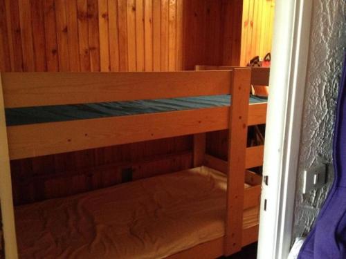 Ce lit superposé se trouve dans un dortoir doté d'un mur en bois. dans l'établissement Appartement AURON + Jardin, à Saint-Étienne-de-Tinée