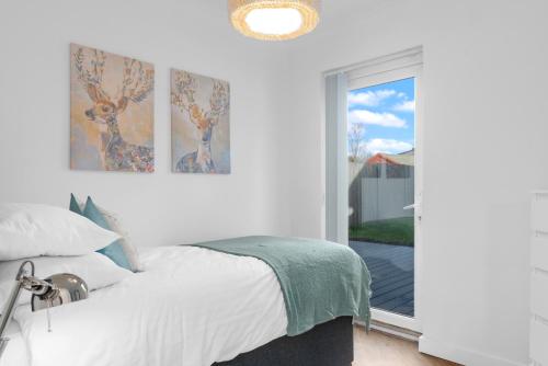 a white bedroom with a bed and a window at Brett Stays - Fast WiFi - Modern Amenities - Smart TV - Sleeps 7 in Avonmouth