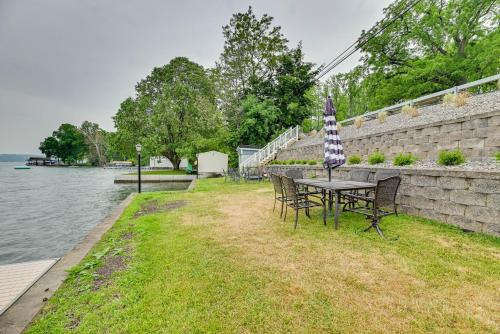 a table and chairs with an umbrella next to the water at Lakefront Canandaigua Home with Dock and Kayak! in Canandaigua