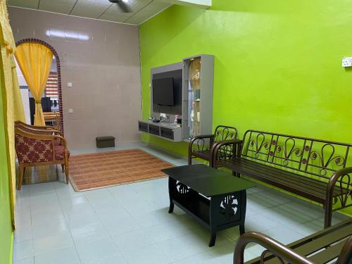 Elle comprend un salon avec des murs verts et une télévision. dans l'établissement 83 Homestay, à Malacca