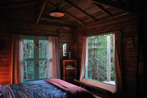 a bedroom with a bed and a large window at Chalé Paiol - Sítio Lajinha in Alagoa