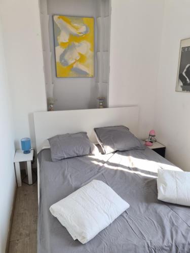 un lit avec deux oreillers et un tableau au mur dans l'établissement La MASCOTTE, à Vallauris