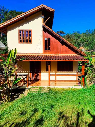 a house in the middle of a green field at Chalé Lumiar M&C in Lumiar