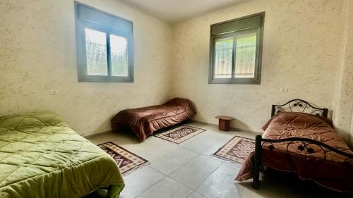 a bedroom with two beds and a couch and two windows at Hebron Hope Guesthouse in Hebron
