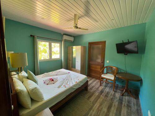 1 dormitorio con 1 cama, TV y silla en Chloe's Cottage Self-Catering en La Digue