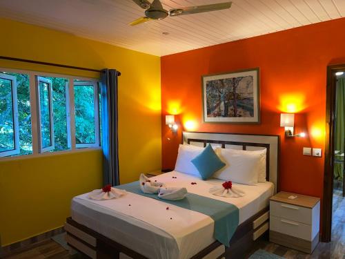 ein Schlafzimmer mit einem Bett mit einer orangefarbenen Wand in der Unterkunft Chloe's Cottage Self-Catering in La Digue