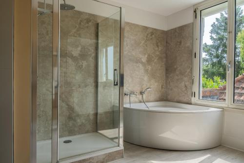 a bathroom with a tub and a glass shower at Chambres d'hotes Lunidor in Lusigny-sur-Barse