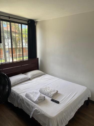 a bed with two towels and a remote control on it at Apartamento laureles Estadio Medellín 203 balcon in Medellín