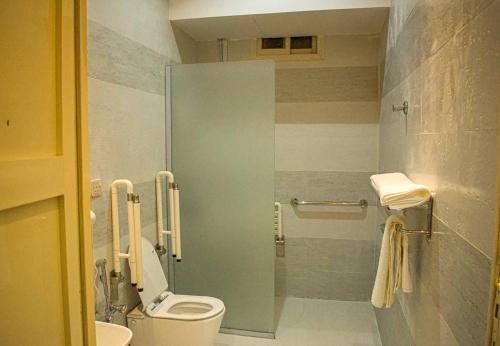 a bathroom with a toilet and a shower stall at ركن الروشن للشقق المخدومه in Hail