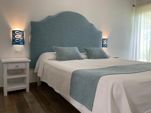 een slaapkamer met een groot bed met een blauw hoofdeinde bij Relais BeneMari in Siniscola