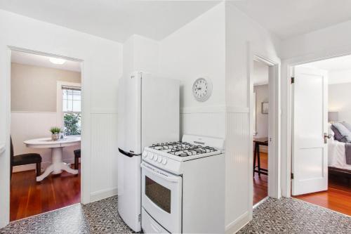 a white kitchen with a stove and a refrigerator at Charming Eugene Retreat Private Hot Tub and Yard! in Eugene