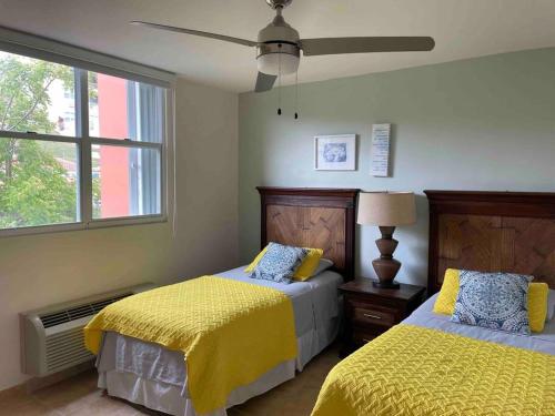 a bedroom with two beds with yellow sheets and a window at 506 Ocean & Marina Views 3 Bedroom 2 Bathroom Lux in Fajardo