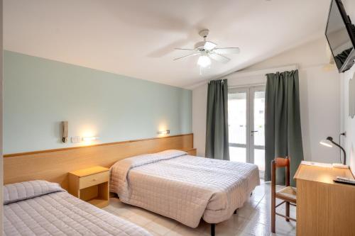 een hotelkamer met 2 bedden en een televisie bij Hotel Itta in Caorle