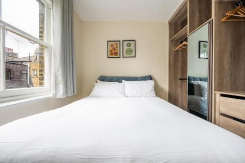 Central London Apartment في لندن: غرفة نوم بسرير ابيض كبير ونافذة