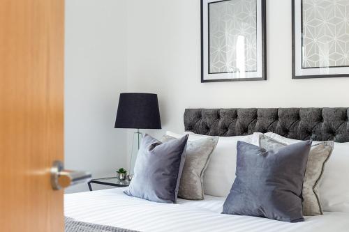 a bedroom with a white bed with blue pillows at Deanery Court Vittrum Suites in Southampton