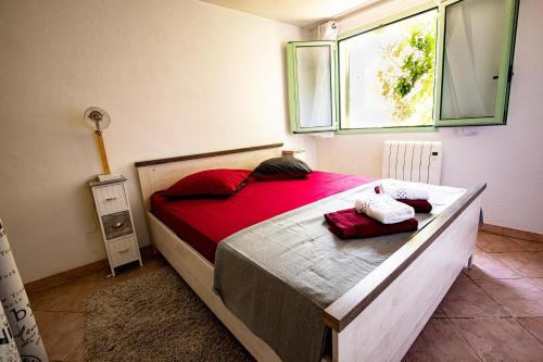 a bedroom with a bed with red sheets and a window at la maison du Vial in Revest-les-Roches