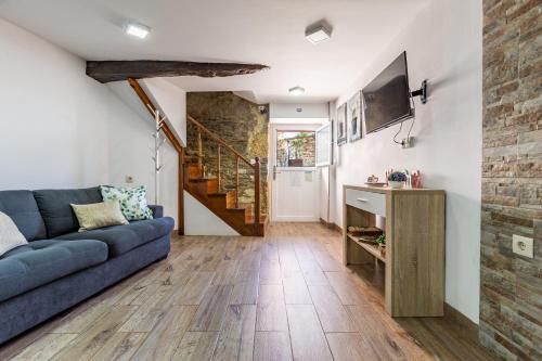 een woonkamer met een blauwe bank en een tv bij Casa do Jornaleiro - Douro in Casal de Loivos