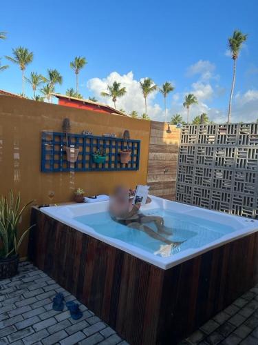 a person in a hot tub with a book in it at Casa_Mare11 in São Miguel do Gostoso