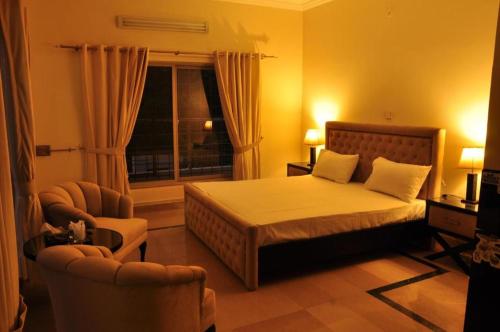 a bedroom with a bed and two chairs and a window at Reina Boutique Hotel - G6 in Islamabad