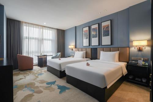 重慶市にあるChongqing Hilman Homeful Hotelのベッド2台とデスクが備わるホテルルームです。