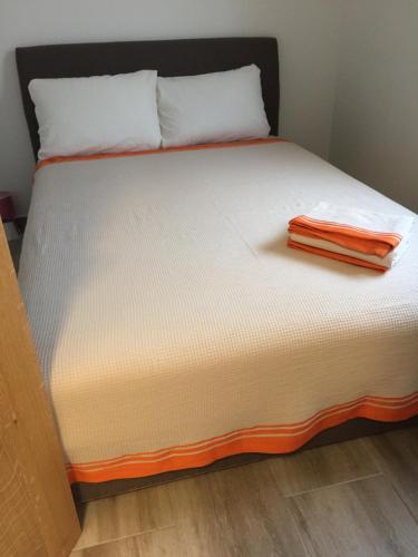 ein Bett mit einem orangenen Handtuch darüber in der Unterkunft Monimont in Golubovci