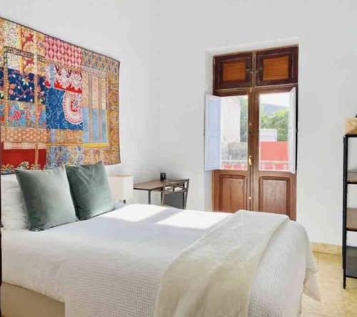 una camera da letto con un letto bianco e un arazzo appeso al muro di CASTILLO LEON AGAETE ad Agaete
