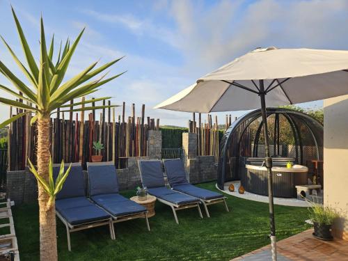 a patio with two chairs and an umbrella at Sunset sea view & garden Spa Cala Tarida 6p max in Cala Tarida