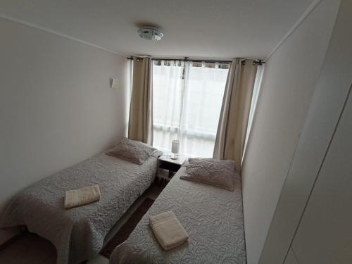 two beds in a small room with a window at Departamento Avda Pacifico La Serena in La Serena