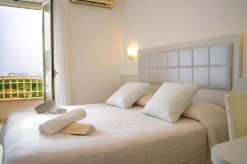 una camera da letto con un grande letto bianco con due asciugamani di Hotel Sirena - Servizio spiaggia inclusive a Peschici