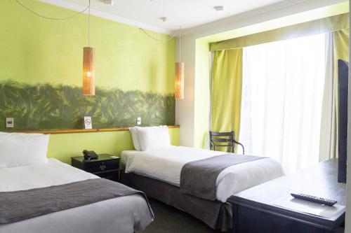 a hotel room with two beds and a window at Hotel Fundador in Santiago