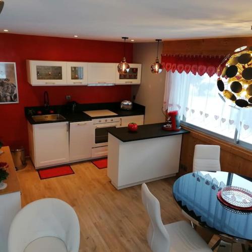 une cuisine avec des armoires blanches et une table et des chaises dans l'établissement Le p'tit Rubis, à Chamonix-Mont-Blanc