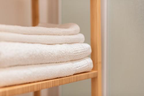 a stack of white towels on a wooden shelf at La Piazzetta in Iseo
