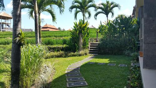 a garden with palm trees and a stone path at Biyukukung Suite & Spa in Ubud