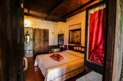 DrapiaにあるAgriturismo Casa del Contadinoのベッドルーム1室(赤いカーテン付きのベッド1台付)