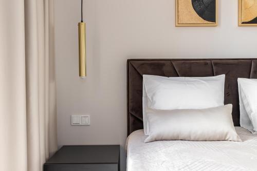 una camera da letto con un letto con lenzuola e cuscini bianchi di Laulupargi Lux Residence a Tallinn