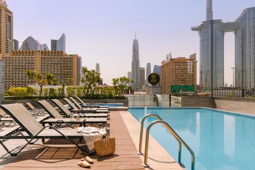 a row of chaise lounge chairs next to a swimming pool at Sonder Downtown Towers in Dubai